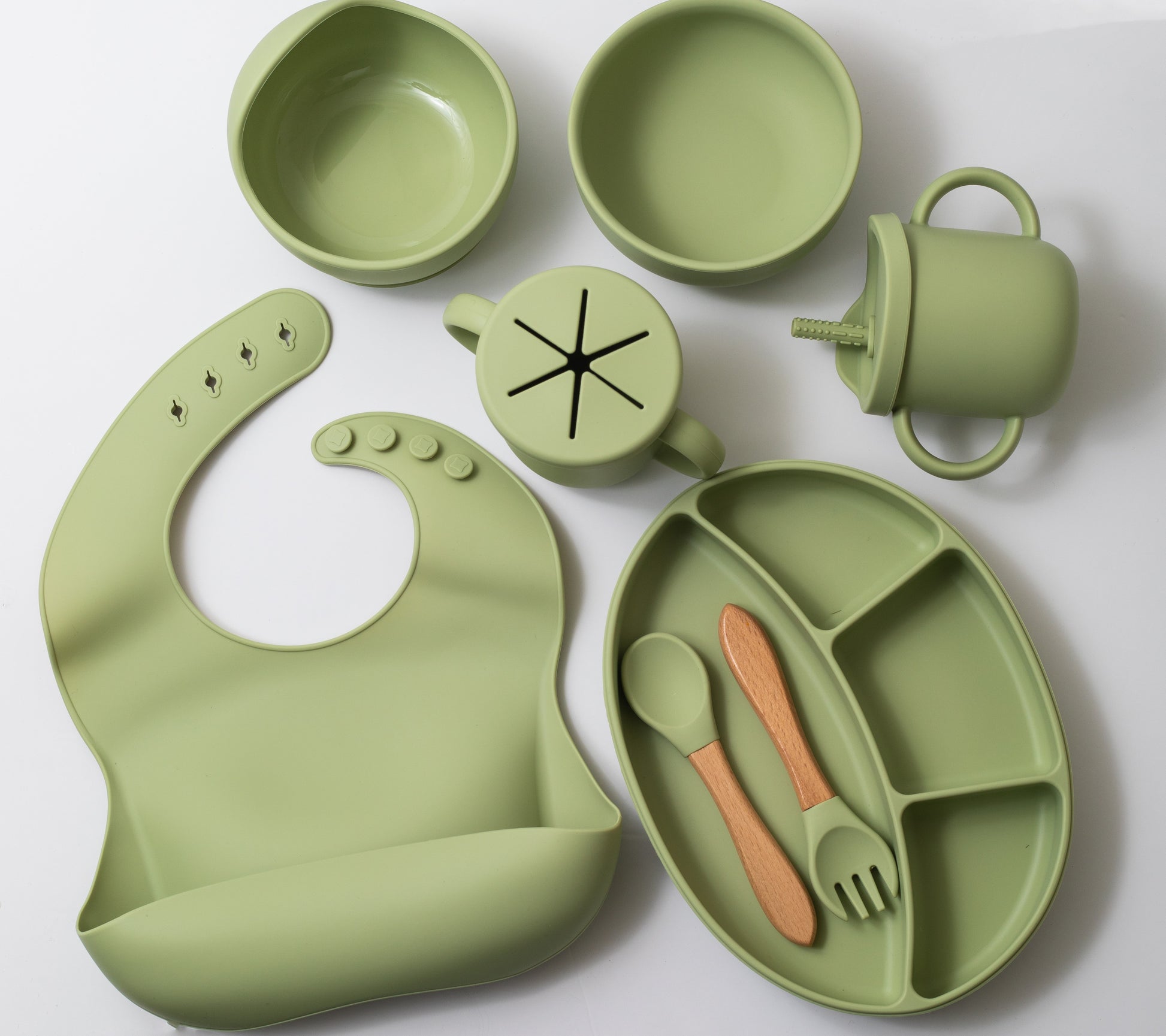 Silicon baby feeding dinner set having weaning bowl round bowl bib sectioned plate spoon sippy cup snack cup and fork in green color